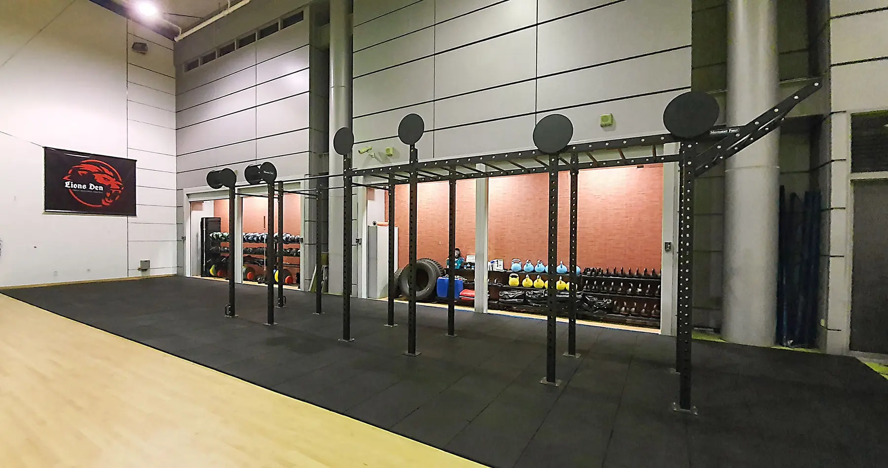 An installed functional fitness rig with overhead bars, wall-ball targets and equipment storage